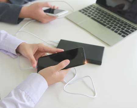 Two people connecting the mobile to a power bank.Technology device charge sharing concept.の写真素材