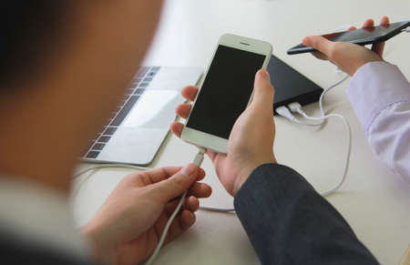 Two people connecting the mobile to a power bank.Technology device charge sharing concept.