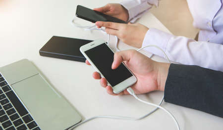 Two people connecting the mobile to a power bank.Technology device charge sharing concept.の写真素材
