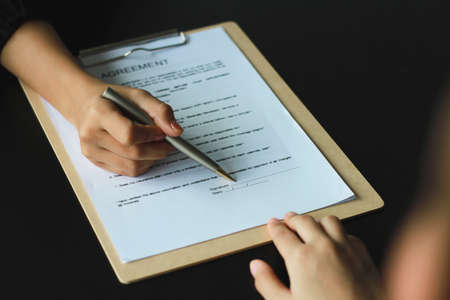 A woman signed a document to become a new employee of the office. Contract and job application...