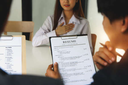 Close-up view of office job interviews with HR personnel holding resume and background checks on applicants with prepared skills.の写真素材