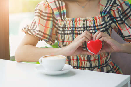 A woman holds a red heart, puts her hand on her chest.の写真素材