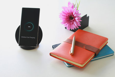Smartphone wireless charging using wireless charging pad new technology at office.の写真素材