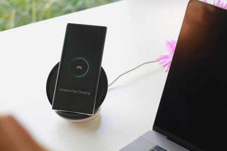 Smartphone wireless charging using wireless charging pad new technology at office.の写真素材