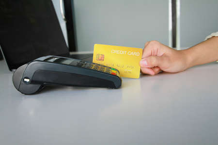 Woman using credit card swipe machine for sell products in the shop to customers. Concept of spending via credit card.の写真素材