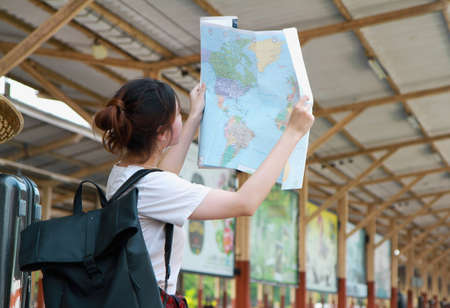 Summer, Travel, Vacation, Relax, A woman with a fresh smile and cute looks at a summer travel map at the train station. Travel conceptの写真素材