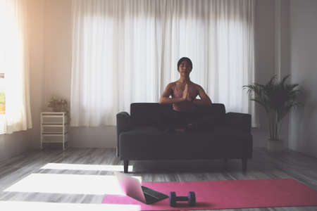 Woman practicing yoga at home from online classes after work. stress relief, muscle relaxation, breathing exercises, exercise, meditation.の写真素材