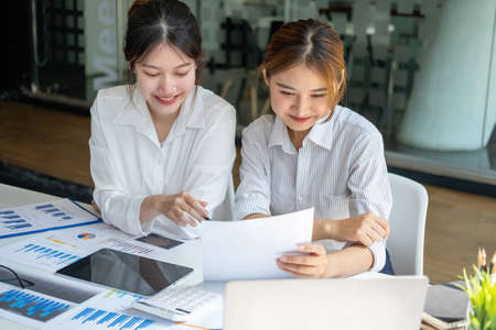 Marketing, Financial, Accounting, Planning, Team of business women analyze company results and profits with graph statistics. Use a laptop computer and a calculator to calculate the company's balance.の写真素材