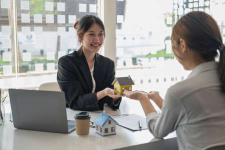 Buying houses and land, guarantees, contract and agreement, An employee of a real estate company hands over the house and keys after the contract for the sale of land and buildings is complete.の写真素材
