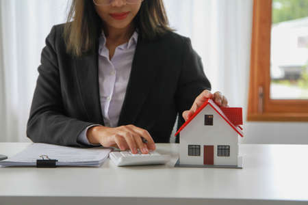 Accountant, businessman, real estate agent, business woman handing model house to customers along with house interest calculation documents for customers to sign.の写真素材