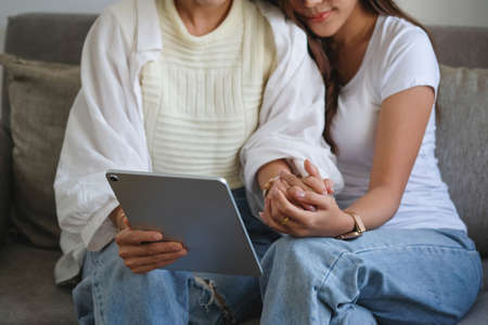 lgbtq, lgbt concept, homosexuality, two beautiful women in love happily playing tablet in a cozy...