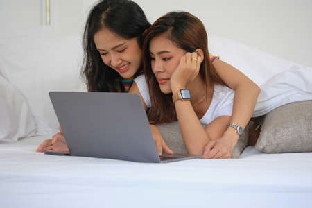 lgbtq lgbt concept homosexuality Two beautiful women happily express their love for each other playing laptop computers in their comfortable homes.の写真素材