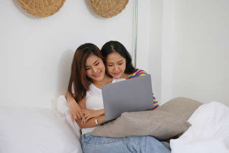lgbtq lgbt concept homosexuality Two beautiful women happily express their love for each other playing laptop computers in their comfortable homes.の写真素材