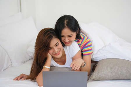 lgbtq lgbt concept homosexuality Two beautiful women happily express their love for each other playing laptop computers in their comfortable homes.の写真素材