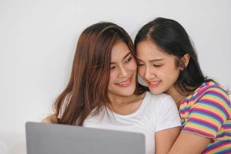 lgbtq lgbt concept homosexuality Two beautiful women happily express their love for each other playing laptop computers in their comfortable homes.の写真素材