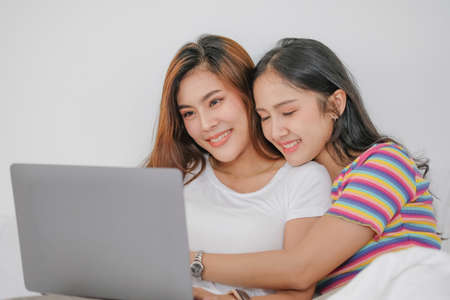 lgbtq lgbt concept homosexuality Two beautiful women happily express their love for each other playing laptop computers in their comfortable homes.の写真素材