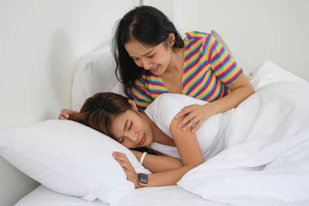 lgbtq, lgbt concept, homosexuality, two beautiful women in love happily playing tablet in a cozy...