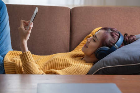 relax, de-stress, holiday, happy, Asian woman relaxing at home listening to music from smartphone...