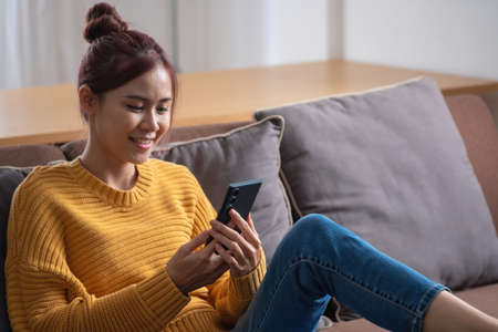 relax, de-stress, holiday, happy, Asian woman relaxing at home listening to music from smartphone and laptop happily.の写真素材
