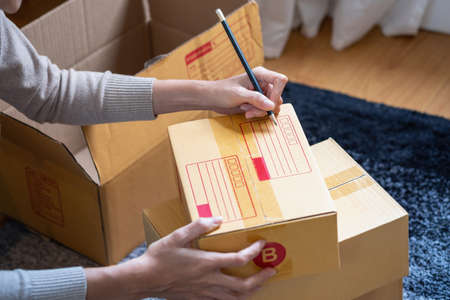 Young Asian SME businessman starting a small and boxed SME business as an online business. Online...