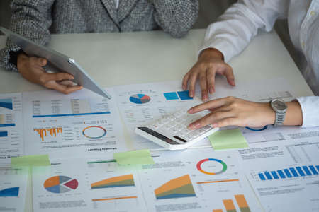 Team of business women use calculators and graph analysis computer laptop tablets to plan marketing strategies and make profitable investments for the company.の写真素材