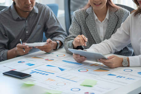 Marketing, Financial, Accounting, Planning, Team of business women analyze company results and profits with graph statistics. Use a laptop computer and a calculator to calculate the company's balance.の写真素材