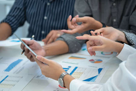 Team of business use calculators and graph analysis computer laptop tablets to plan marketing...