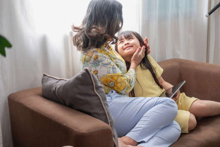 Portrait of an elderly woman and granddaughter reading tablet to enhance reading skills and family...