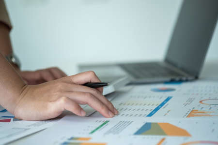 Marketing, Finance, Accounting, Planning, Businesswomen use calculators, computers, and graphs to analyze work to make the company profitable.の写真素材