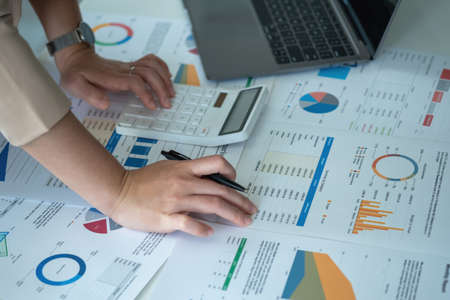 Marketing, Finance, Accounting, Planning, Businesswomen use calculators, computers, and graphs to analyze work to make the company profitable.の写真素材
