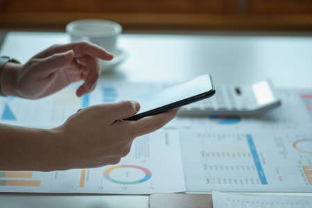An Asian businesswoman uses a mobile phone to contact a customer to inform her of the company's business partnership.の写真素材