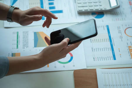 An Asian businesswoman uses a mobile phone to contact a customer to inform her of the company's...