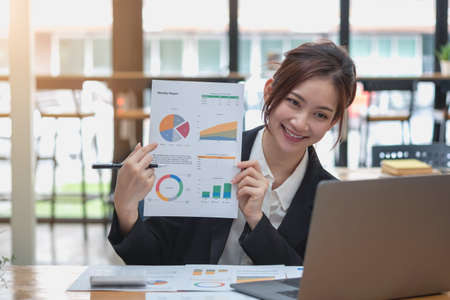 Marketing, Financial, Accounting, Planning, Business women analyze company results and profits with graph statistics. Use a laptop computer and a calculator to calculate the company's balance.の写真素材
