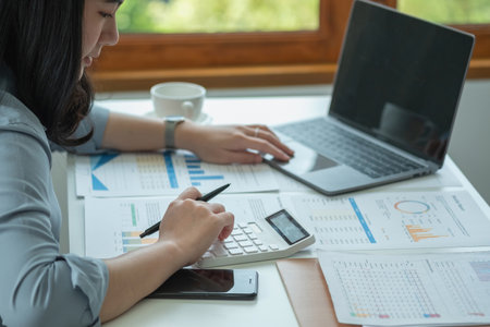 Businesswoman presenting profit data with graphs to her supervisor via laptop computer.の写真素材