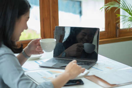Businesswoman presenting profit data with graphs to her supervisor via laptop computer.の写真素材