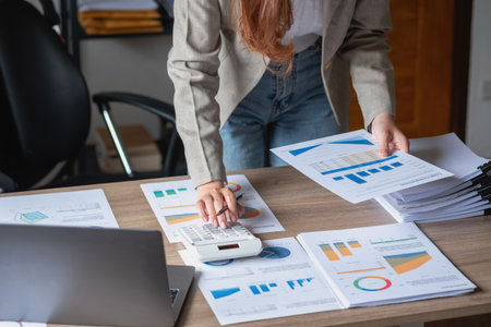marketing, finance, accounting, planning, female accountant using laptop calculator and documents, charts, graphs in the analysis of the company's profitの写真素材