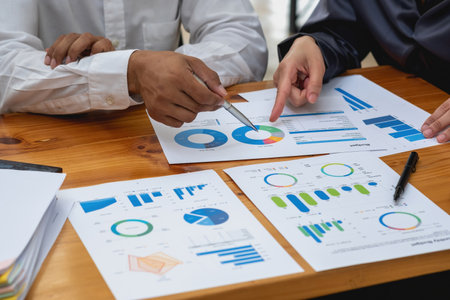 The company's team of marketers analyzes the company's profits using laptop computer graphs and calculators.の写真素材