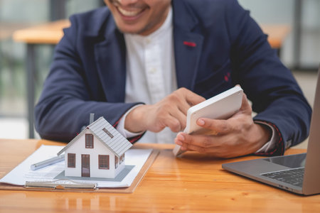 Accountant, businessman, real estate agent, businessman handing model house to customers along with house interest calculation documents for customers to sign.の写真素材