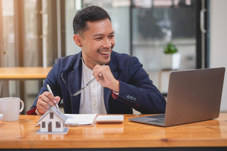 Accountant, businessman, real estate agent, businessman handing model house to customers along with house interest calculation documents for customers to sign.の写真素材