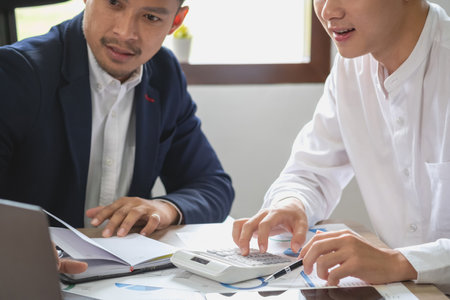 Team of business use calculators and graph analysis computer laptop tablets to plan marketing strategies and make profitable investments for the company.の写真素材