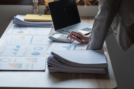 Marketing, Financial, Accounting, Planning, business women analyze company results and profits with graph statistics. Use a laptop computer and a calculator to calculate the company's balance.の写真素材