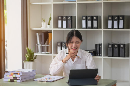 Portrait of a female accountant using a calculator and laptop to calculate balance using graphs for customers.の写真素材