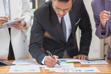 Marketing, Finance, Accounting, Planning, A team of businessmen plan with their laptops and graph charts for their profits and use a calculator to calculate their company is annual balance.の写真素材