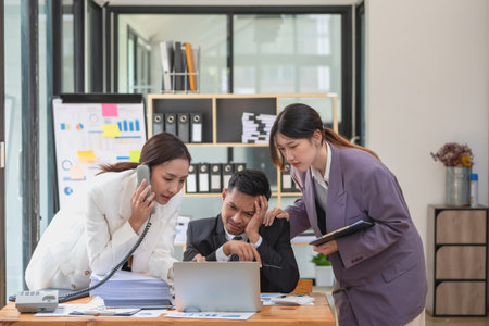A team of business people are busy working on the phone. laptop computer and document graphs in working within the officeの写真素材
