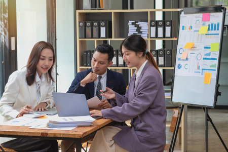 Marketing, Finance, Accounting, Planning, A team of businessmen plan with their laptops and graph charts for their profits and use a calculator to calculate their company is annual balance.の写真素材