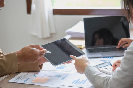 Team of business use calculators and graph analysis computer laptop tablets to plan marketing strategies and make profitable investments for the company.の写真素材