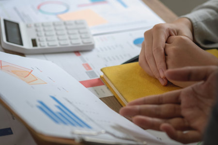 Marketing, Finance, Accounting, Planning, A team of businessmen plan with their laptops and graph charts for their profits and use a calculator to calculate their company is annual balance.の写真素材