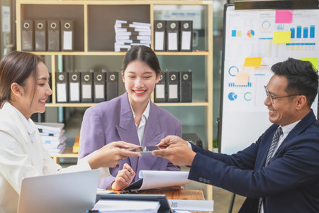 Asian business team consists of marketing staff. accountant and financial officer Help each other analyze company profits using tablets. calculator Laptop computers, graph paper, and corporate pens.の写真素材