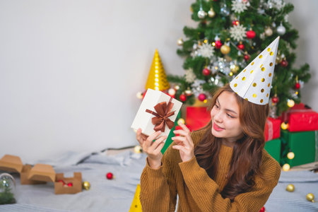 Merry Christmas and Happy Holidays! Young woman with a beautiful face in a yellow shirt shows joy...