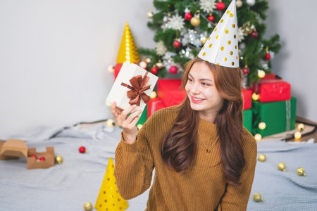 Merry Christmas and Happy Holidays! Young woman with a beautiful face in a yellow shirt shows joy...
